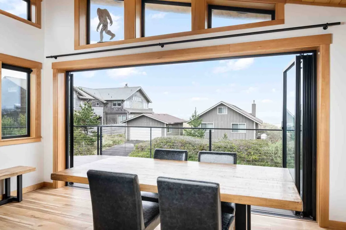 A bright dining area with a family-sized table positioned beside expansive windows, offering inviting views of the outdoors. The natural light floods the space, making it ideal for meals and memorable conversations.
