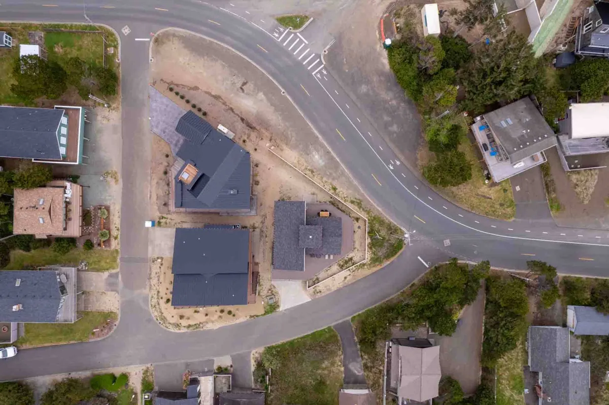 An exterior shot showing a curved road, modern houses, and green landscaping. The setting is calm and well-maintained, suggesting convenient access, free parking, and a peaceful neighborhood.