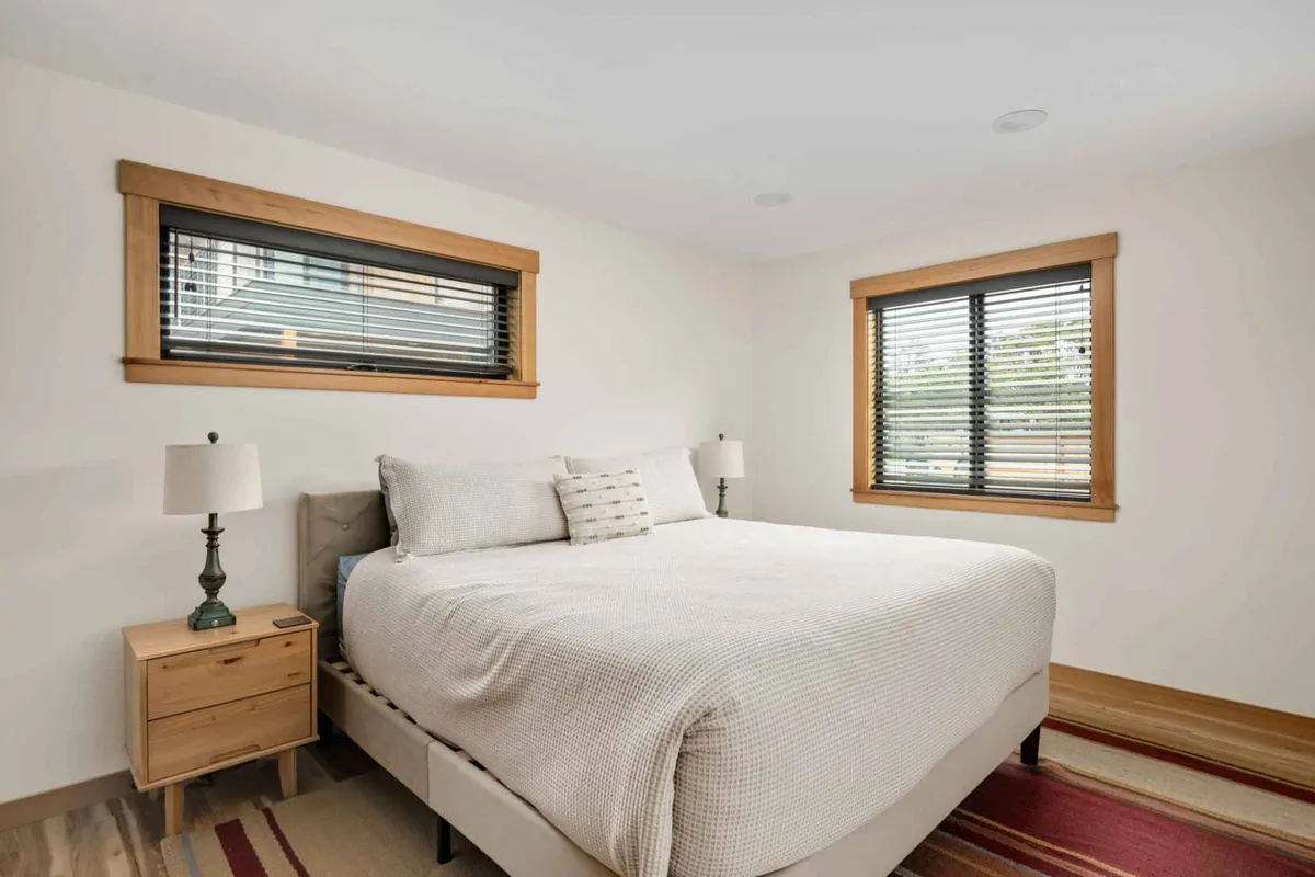 A tranquil bedroom featuring a plush king-sized bed with upscale linens, a nightstand with stylish lamps, and large windows allowing soft natural light to fill the space. The overall atmosphere is peaceful and inviting, creating an ideal retreat for restful sleep.