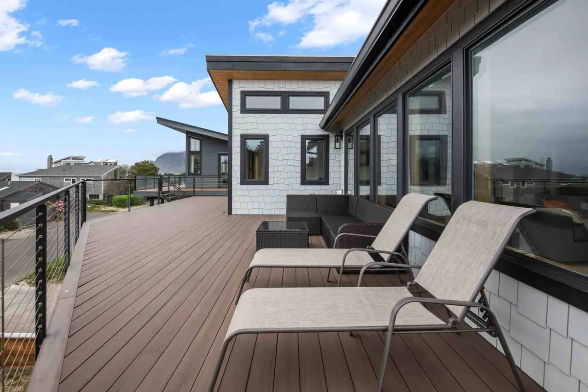 A serene wraparound deck with comfortable outdoor seating, panoramic views, and space for relaxation or entertaining. The setting invites guests to enjoy ocean breezes and extend their living space outdoors.