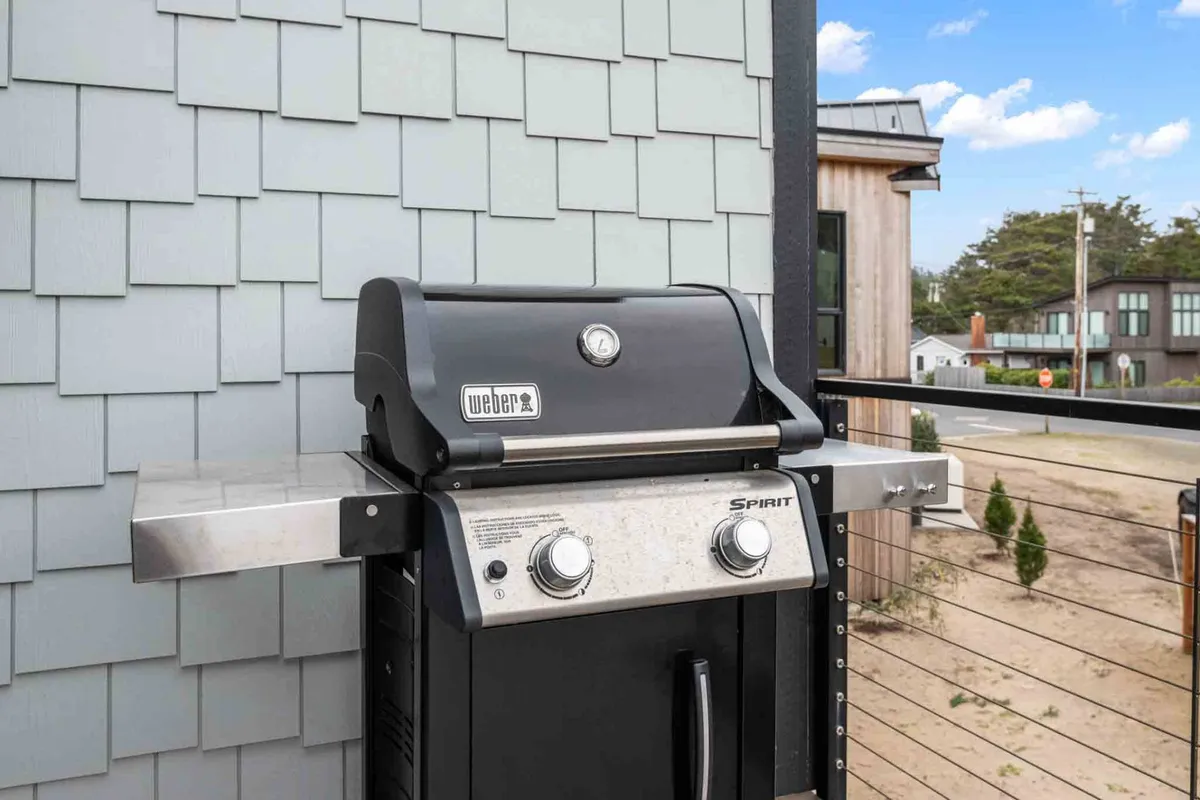 A BBQ grill sits on the deck adjacent to the railings, with a scenic view in the background. This setup highlights a dedicated grilling zone, ideal for outdoor cooking, creating memorable meals, and enjoying the ocean breeze while dining al fresco.
